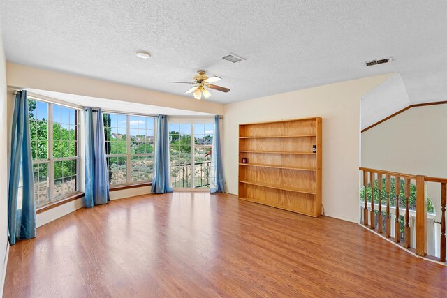 empty room featuring ceiling fan, wood-type flooring, and a textured ceiling