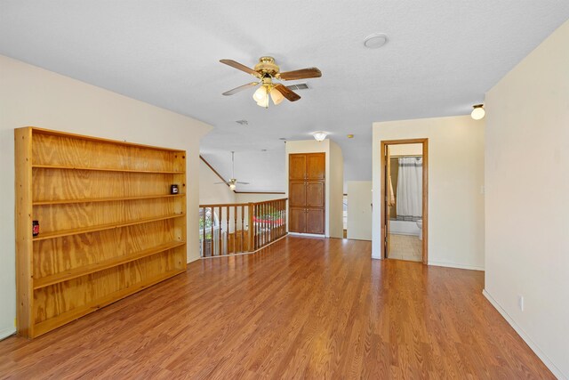 unfurnished living room with a textured ceiling, hardwood / wood-style floors, and ceiling fan