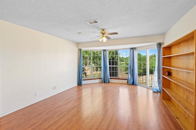 spare room featuring ceiling fan, light wood-type flooring, and a textured ceiling