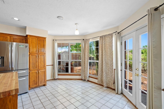 kitchen featuring french doors, decorative light fixtures, stainless steel fridge, wood counters, and a textured ceiling