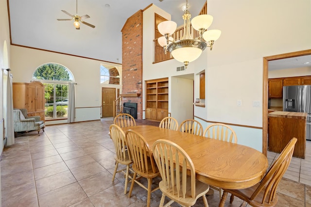 tiled dining area featuring a fireplace, high vaulted ceiling, and ceiling fan with notable chandelier