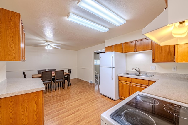 kitchen with ceiling fan, sink, white appliances, and a textured ceiling