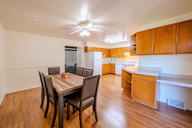 dining space with a textured ceiling, ceiling fan, and light hardwood / wood-style floors