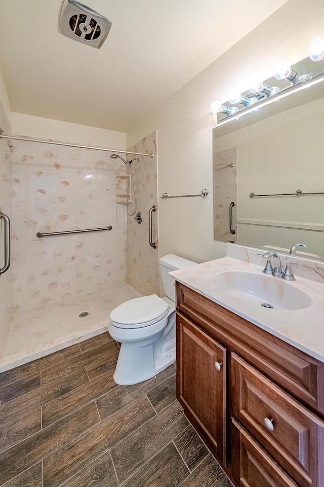 bathroom with toilet, vanity, and a tile shower