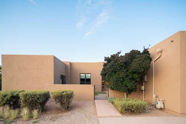 southwest-style home featuring fence, a gate, and stucco siding