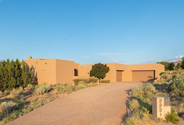 pueblo-style home with a garage, an outbuilding, and stucco siding