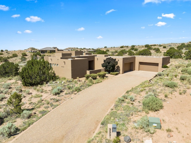 pueblo revival-style home featuring a garage and stucco siding