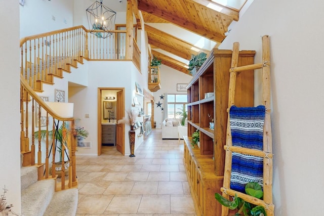 foyer featuring beamed ceiling, high vaulted ceiling, a skylight, light tile patterned floors, and an inviting chandelier