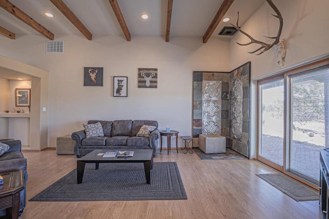 living room featuring beamed ceiling and light wood-type flooring