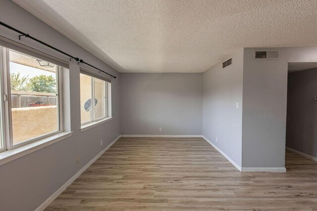 spare room featuring light hardwood / wood-style flooring and a textured ceiling