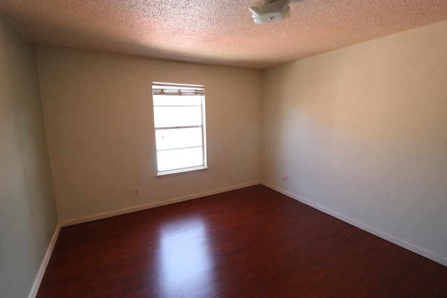 spare room featuring dark hardwood / wood-style floors and a textured ceiling