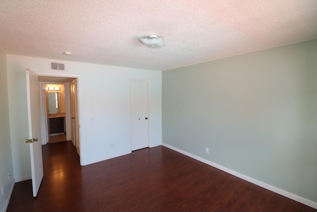 unfurnished bedroom with dark hardwood / wood-style flooring and a textured ceiling