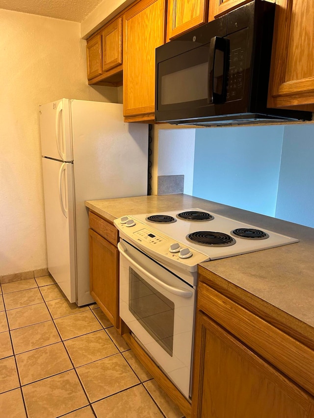 kitchen with white appliances, light tile patterned floors, and a textured ceiling