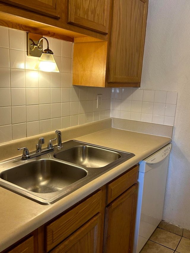 kitchen with white dishwasher, sink, light tile patterned floors, and backsplash