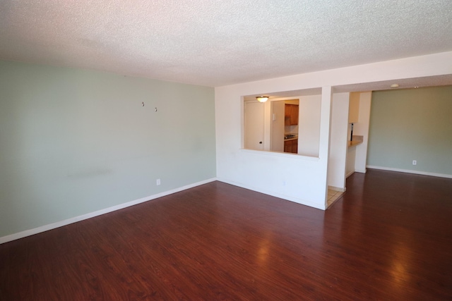 spare room featuring dark wood-type flooring and a textured ceiling