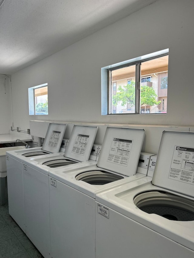 laundry area featuring a textured ceiling, plenty of natural light, and washer and dryer