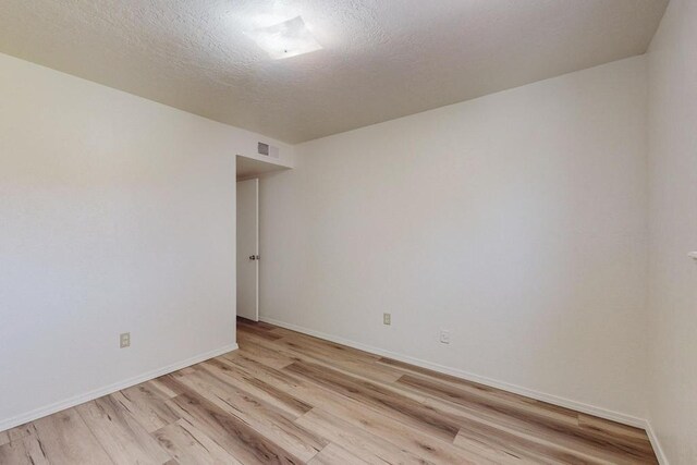 spare room featuring light wood-type flooring and a textured ceiling