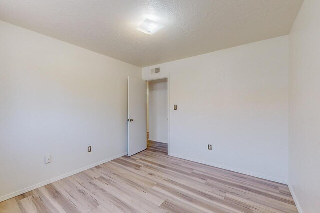 unfurnished room with a textured ceiling and light hardwood / wood-style flooring