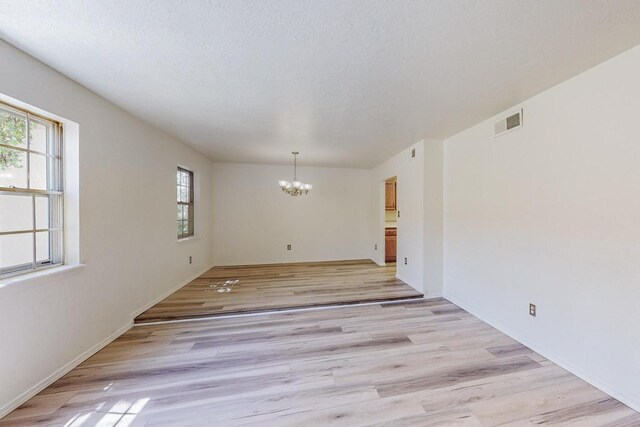 unfurnished room featuring light wood-type flooring and a notable chandelier