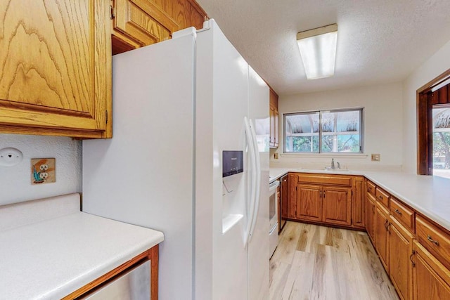 kitchen featuring sink, stove, light wood-type flooring, and white refrigerator with ice dispenser