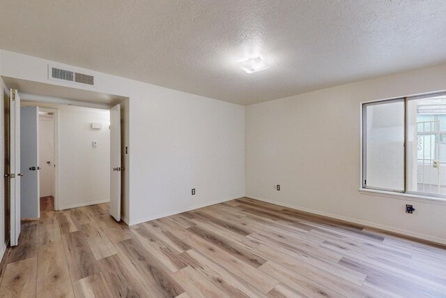 spare room with a textured ceiling and light wood-type flooring