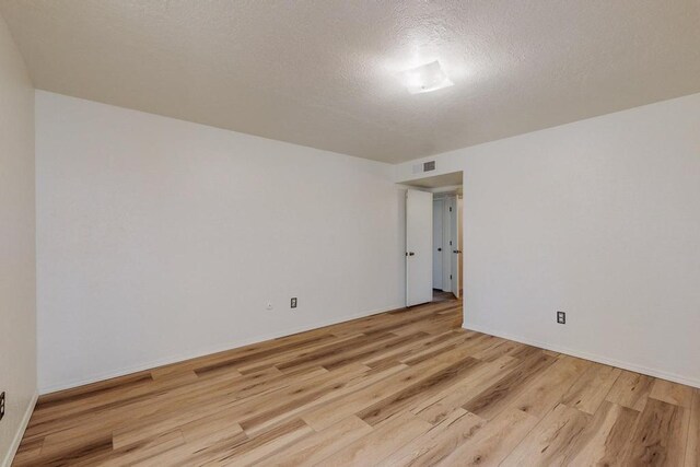 spare room featuring a textured ceiling and light hardwood / wood-style flooring