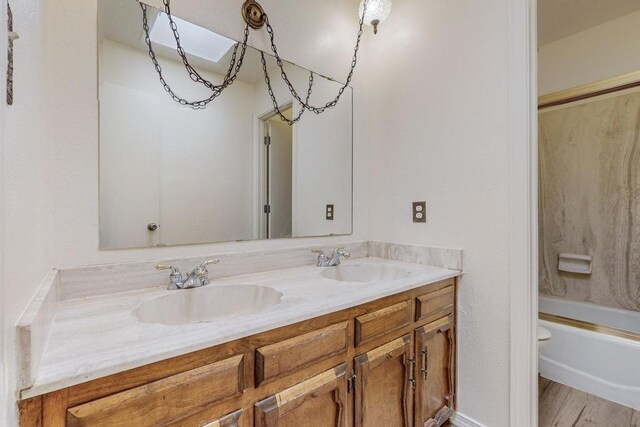 full bathroom with shower / tub combination, dual vanity, wood-type flooring, and toilet