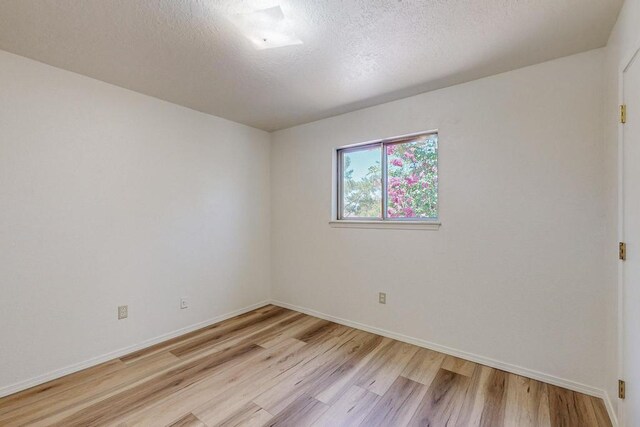 unfurnished room with light hardwood / wood-style flooring and a textured ceiling