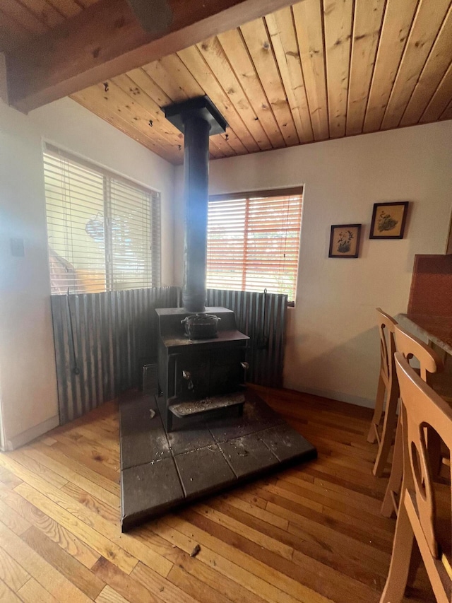 interior space with a wood stove, light wood-type flooring, and wooden ceiling