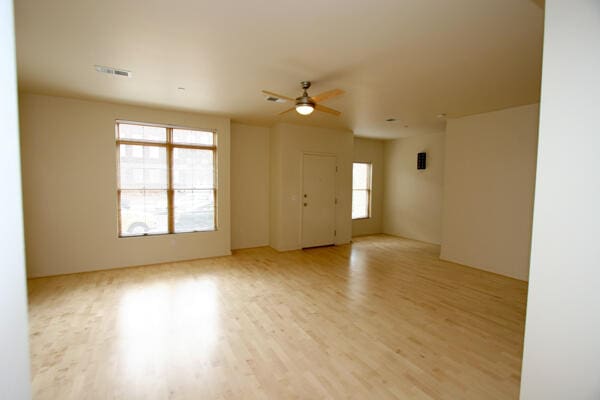 empty room with light hardwood / wood-style floors, ceiling fan, and plenty of natural light