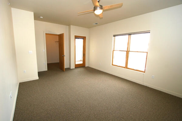 empty room featuring dark colored carpet and ceiling fan