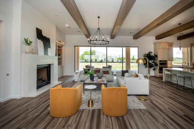 living room with an inviting chandelier, beam ceiling, and dark wood-type flooring