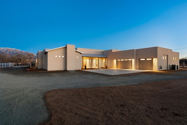 back house at dusk with a garage and a mountain view