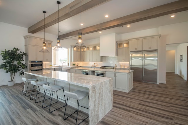 kitchen featuring a kitchen island, appliances with stainless steel finishes, dark hardwood / wood-style floors, beamed ceiling, and decorative light fixtures