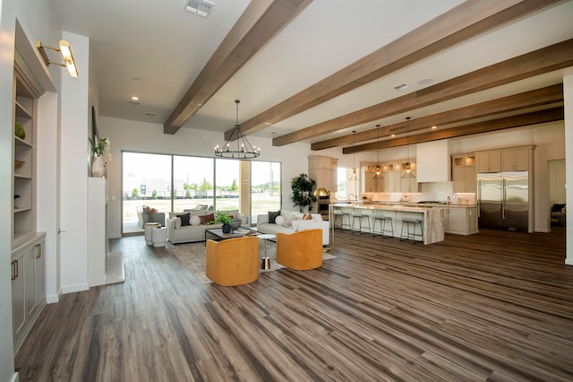 living room with beamed ceiling, sink, dark hardwood / wood-style floors, and an inviting chandelier