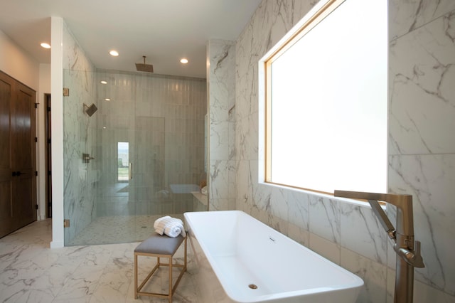 bathroom featuring shower with separate bathtub and tile walls