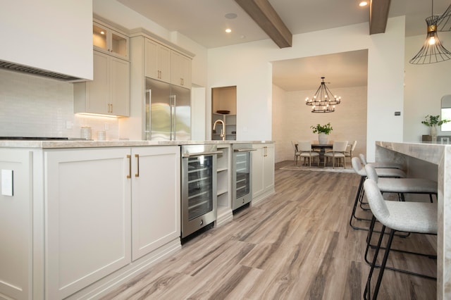 kitchen with stainless steel built in fridge, beam ceiling, light wood-type flooring, and beverage cooler