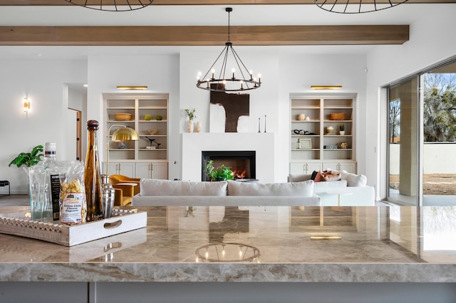 unfurnished living room with a notable chandelier, beam ceiling, and plenty of natural light