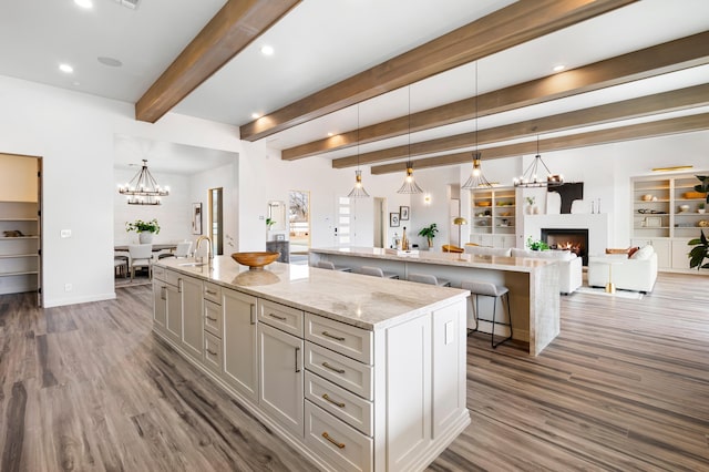 kitchen with a spacious island, sink, hanging light fixtures, and dark wood-type flooring