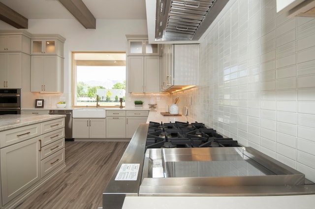 kitchen featuring sink, stainless steel appliances, beam ceiling, decorative backsplash, and dark hardwood / wood-style floors