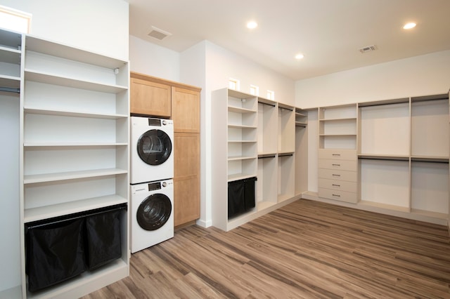 clothes washing area with hardwood / wood-style floors and stacked washer / drying machine