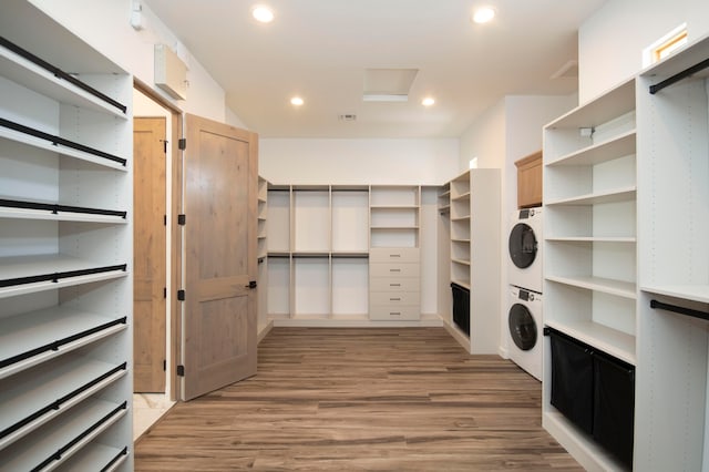 walk in closet with stacked washing maching and dryer and light wood-type flooring