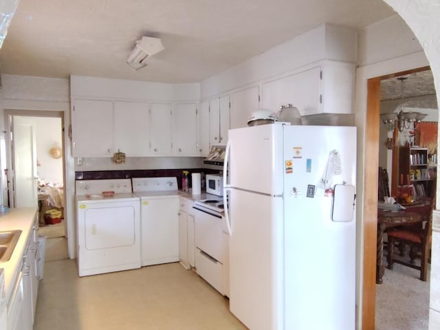 kitchen featuring white appliances, white cabinets, and separate washer and dryer