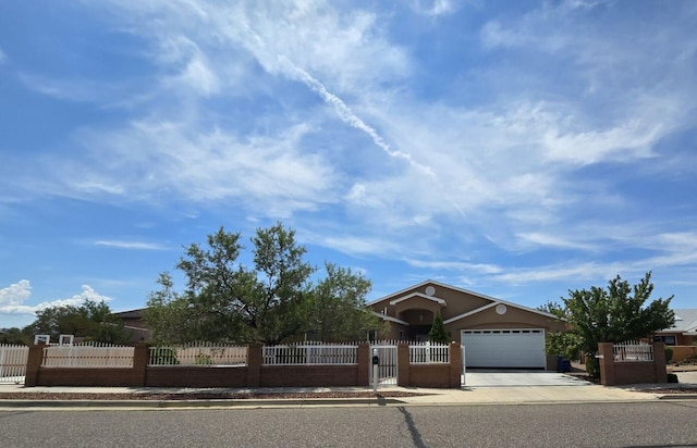 view of front of property with a fenced front yard, an attached garage, driveway, and a gate