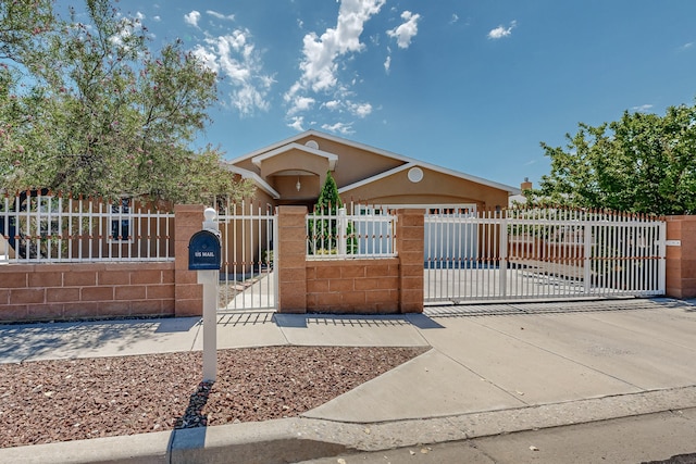 view of front of property with a gate, driveway, an attached garage, stucco siding, and a fenced front yard