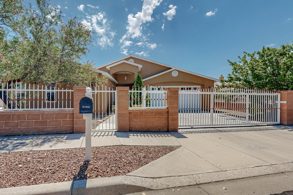 view of front facade featuring stucco siding, a gate, and a fenced front yard