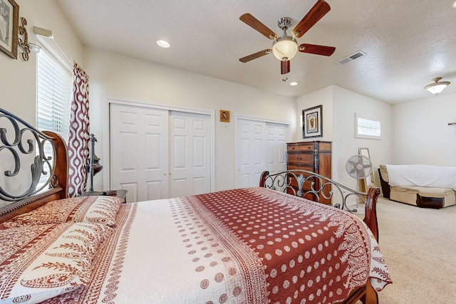 bedroom featuring visible vents, carpet, multiple closets, recessed lighting, and a ceiling fan