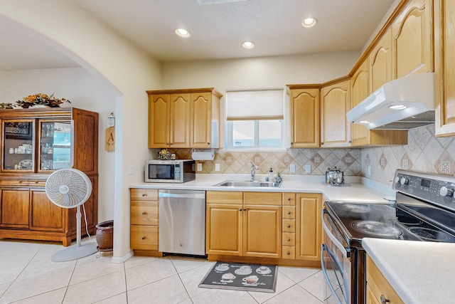 kitchen featuring light tile patterned floors, a sink, stainless steel appliances, light countertops, and under cabinet range hood