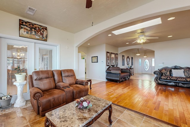 living room with visible vents, a ceiling fan, recessed lighting, arched walkways, and light wood-style floors