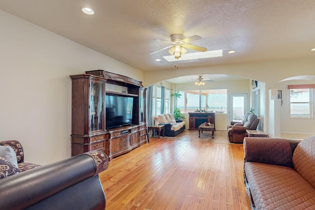 living area featuring a textured ceiling, recessed lighting, arched walkways, light wood finished floors, and ceiling fan